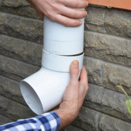 Contractor hands repair, install rain gutter downspout pipe. Rain Chain Drainage. Guttering Down pipe Fittings