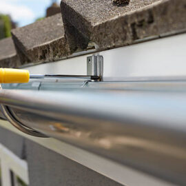 Close Up Of Man Replacing Guttering On Exterior Of House